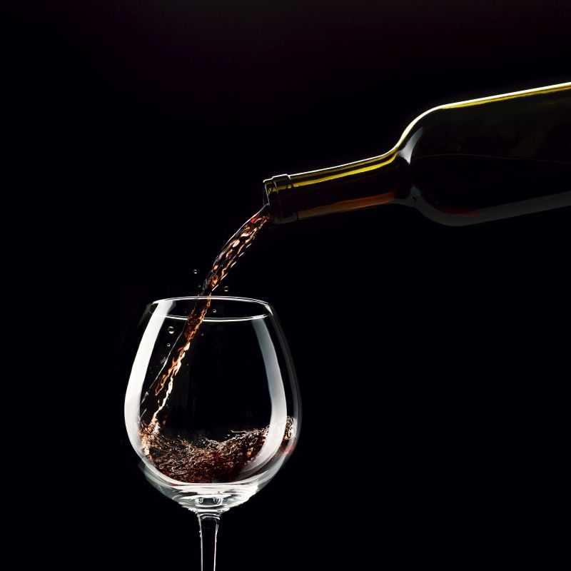Pouring excellent red wine in a wineglass, wine tasting concept, low key